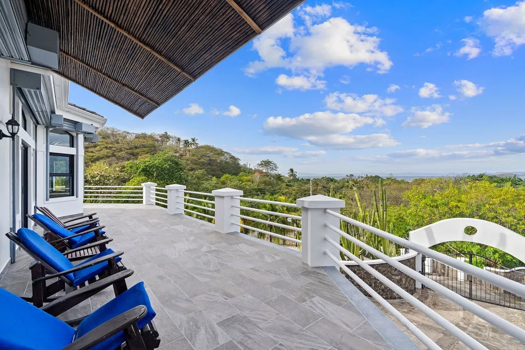 Upper terrace with blue Adirondack chairs overlooking the treetops to the Pacific