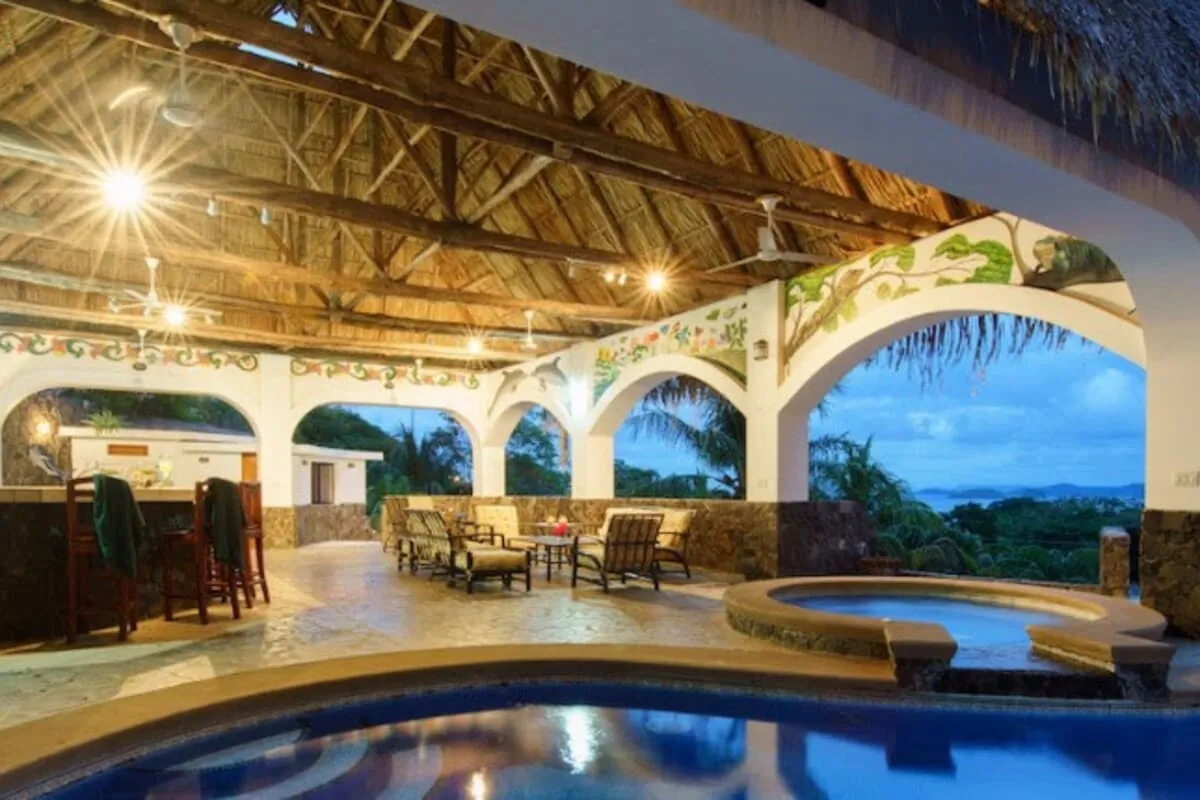 Pool and waterfall jacuzzi under the rancho at dusk with ocean view